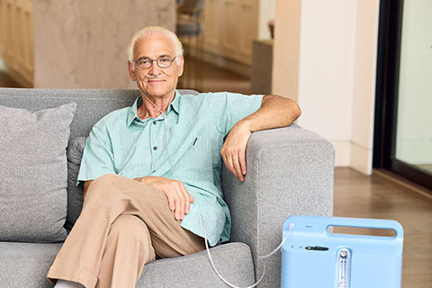 Oxygen WhiteMale SittingOnCouch OxygenConcentrator RespironicsEverflow 5LPM 2
